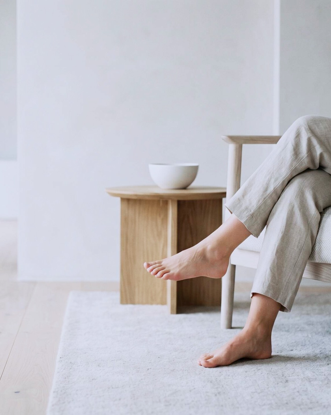 Bare feet up on a wooden side table in a calm minimalist living room